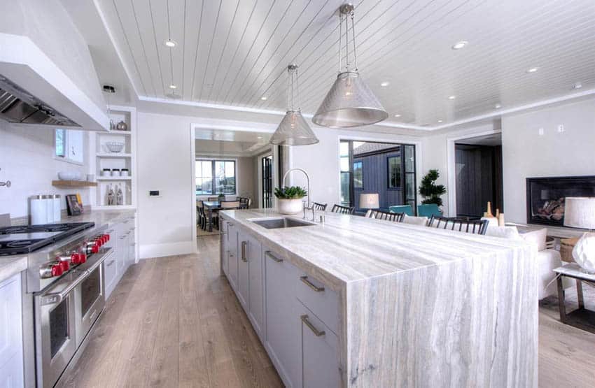 Contemporary kitchen with open concept to living room and waterfall travertine counter island