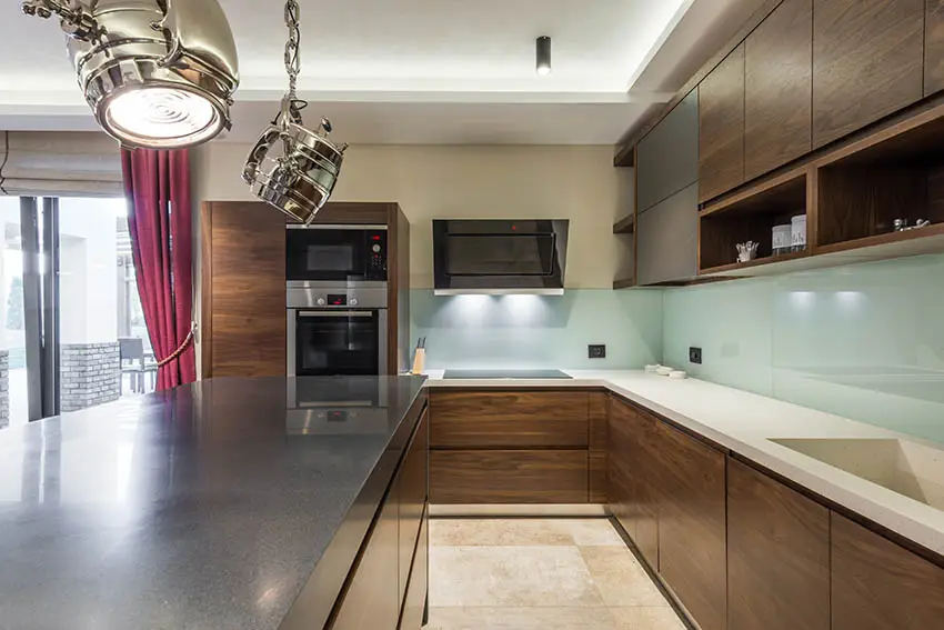 Kitchen with european flat panel cabinets with no hardware and aqua blue glass backsplash