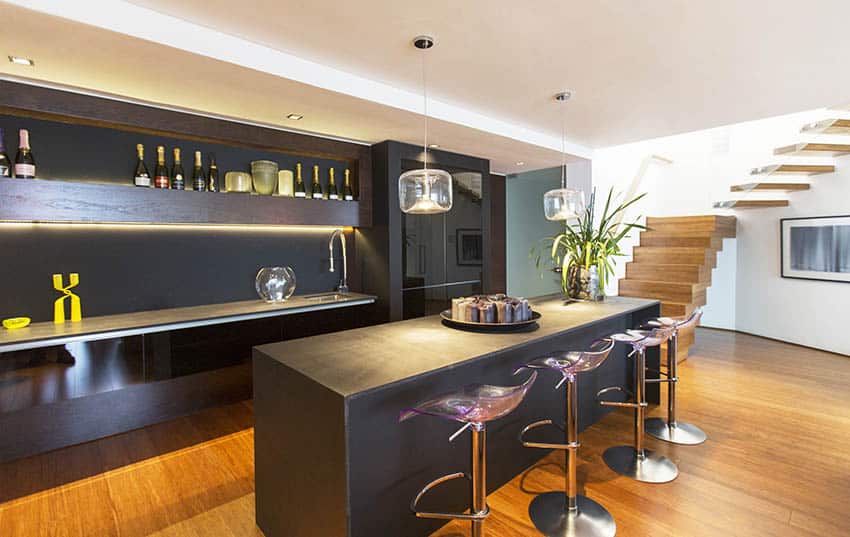 Large modern basement home bar with black cabinets slate countertops under cabinet lighting