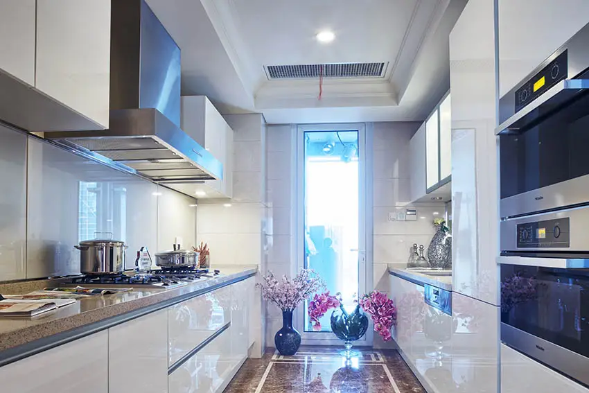 Small modern galley kitchen with high gloss white cabinets and marble floors