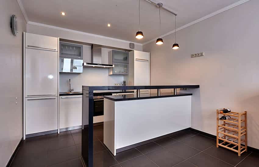 Small modern kitchen with white cabinets black breakfast bar and tile floor