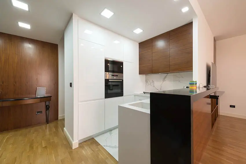 Small modern kitchen with white high gloss cabinets and black countertop