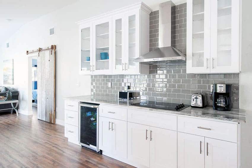 Small one wall open plan kitchen with white cabinets and gray tile backsplash