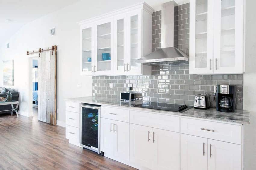 Small one wall kitchen with white shaker cabinets and gray backsplash