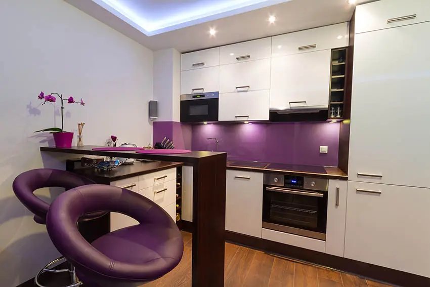 Small white modern kitchen with purple backsplash and purple bar stools