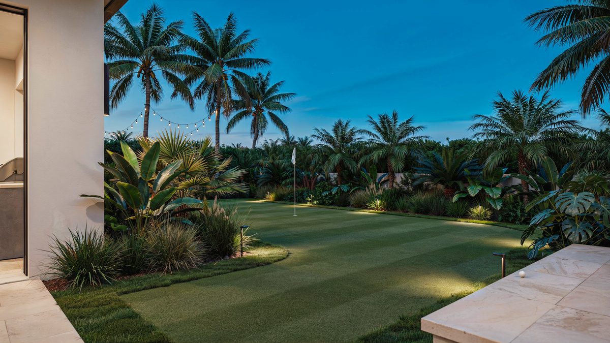 Palm framed green glowing under dusk uplighting at a tropical luxury home