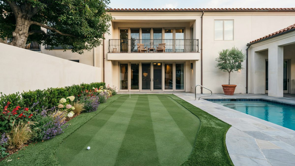 Striped green between a flower border and pool below a second floor balcony