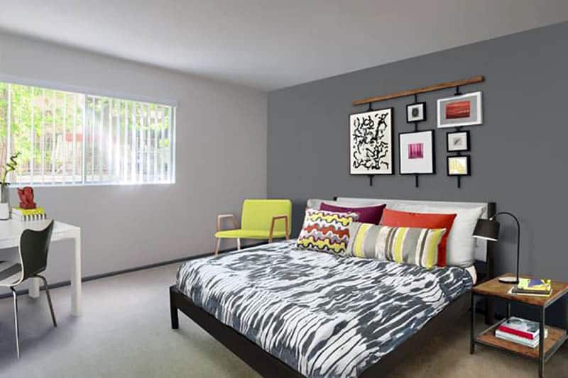 Bedroom with light and dark gray walls, lime green cushions and wall decor