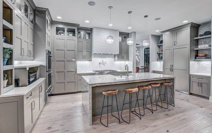 Contemporary light gray kitchen cabinets, light wood floors and white textured backsplash