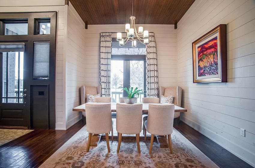 Dining room with white shiplap walls and dark wood floors with area rug