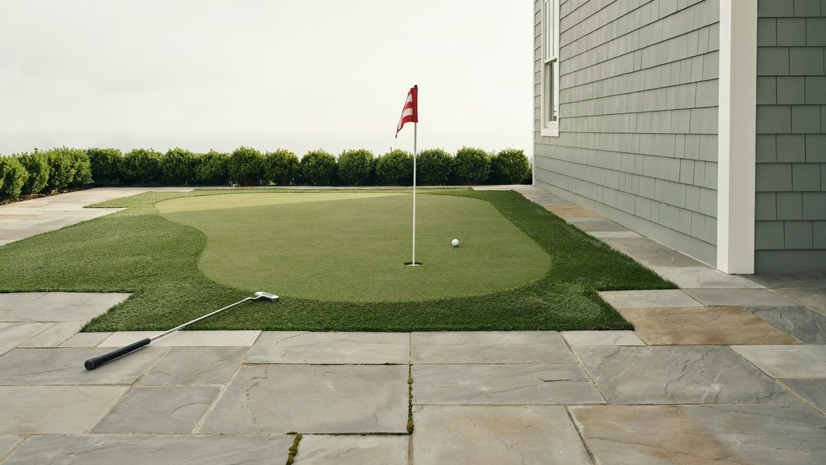 Turf panel set flush into bluestone paving against gray shingle siding