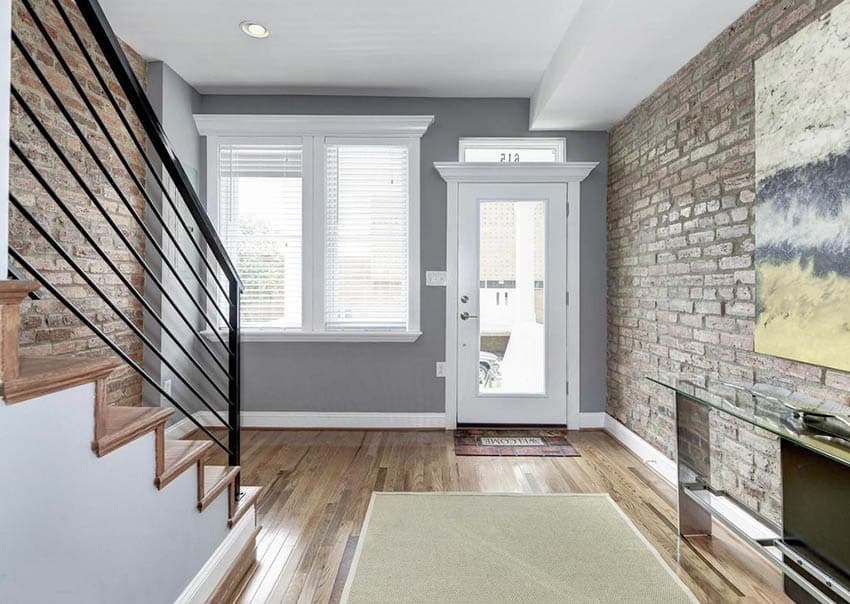 Home entryway with gray paint, white door, wood floor and brick walls