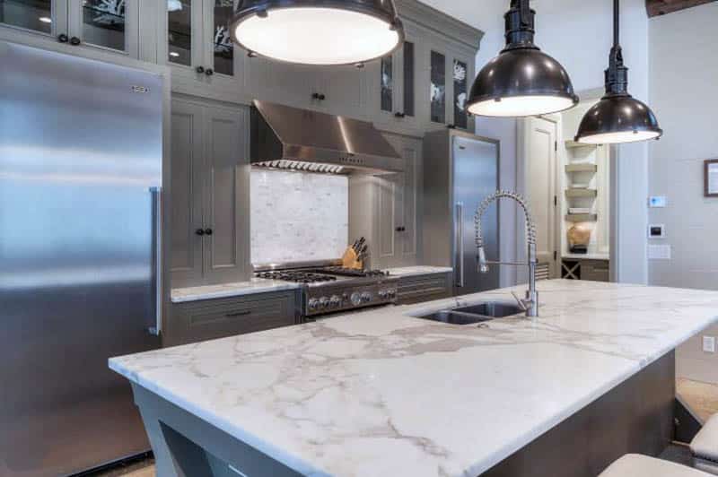 Kitchen with dark grey cabinets calacatta carrara marble countertops and pendant lighting