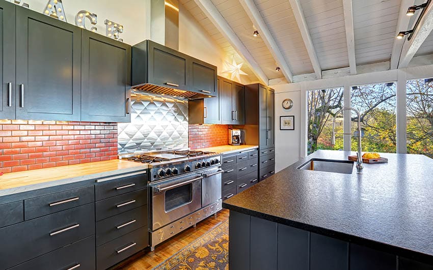 Kitchen with gray cabinets and island with brick wall backsplash and stainless steel stove backsplash