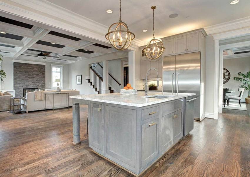 Kitchen with slightly distressed gray cabinets and carrara marble countertops with gold globe pendant lights