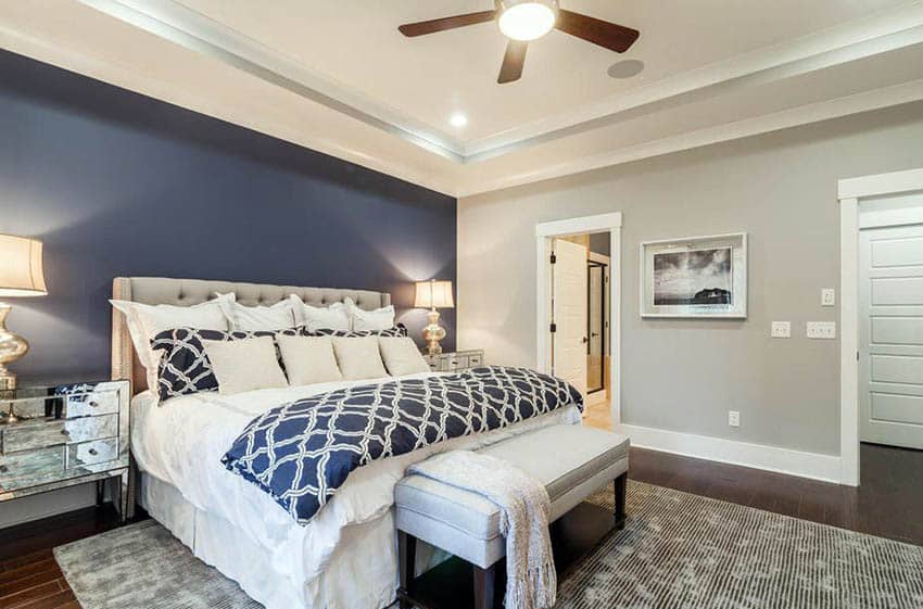 Master bedroom with light gray walls and dark blue accent wall behind tufted bed