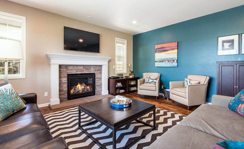 Room with television above white mantel, coffee table and turquoise walls