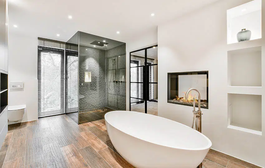Luxe modern bathroom with charcoal glass walk in shower, freestanding tub & wood look tile floors