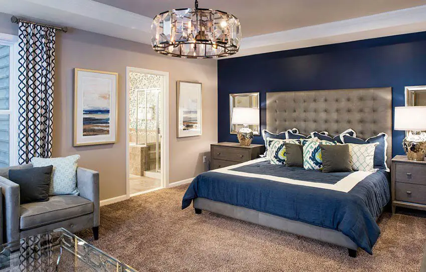 Room with drum chandelier, curtains, bed with gray headboard and windows