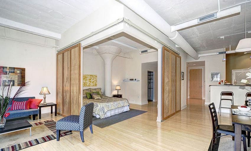 Studio apartment room bedroom combo with sliding barn doors and bamboo flooring