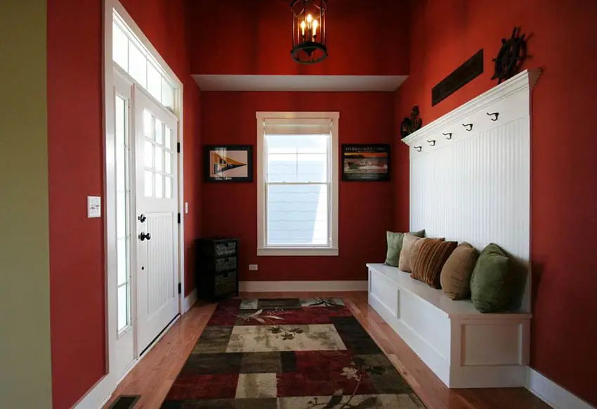 Tomato red entryway with wood floors and white coat rack bench