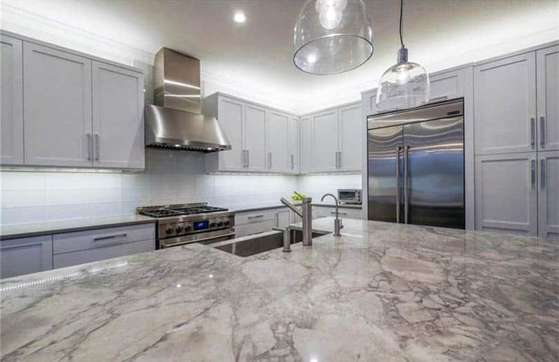 Transitional kitchen with light gray cabinets white tile backsplash island and carrara marble counters