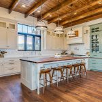 Country kitchen with Bianco Carrara marble counters and exposed beam ceiling