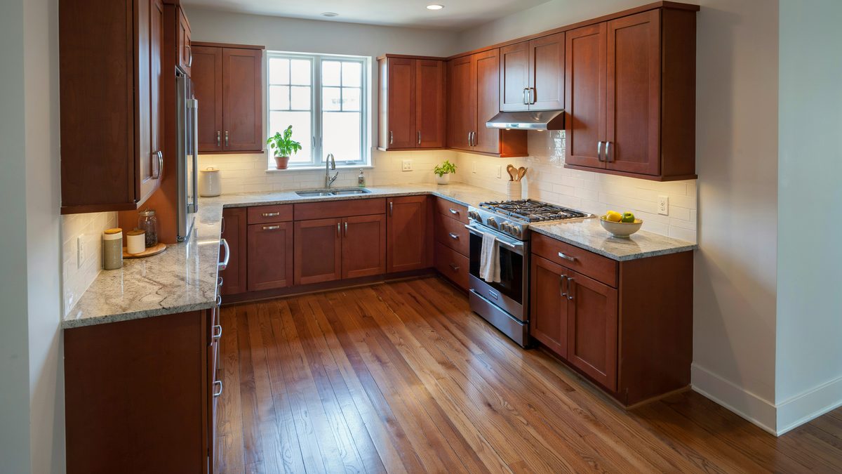 Deep cherry cabinets form an L layout with speckled granite counters