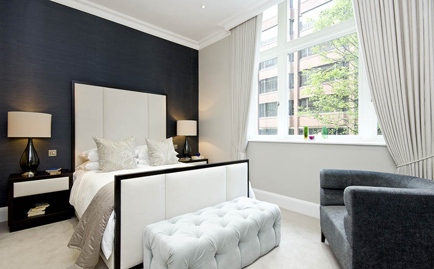 White bedroom with high headboard and wall painted in matte black paint