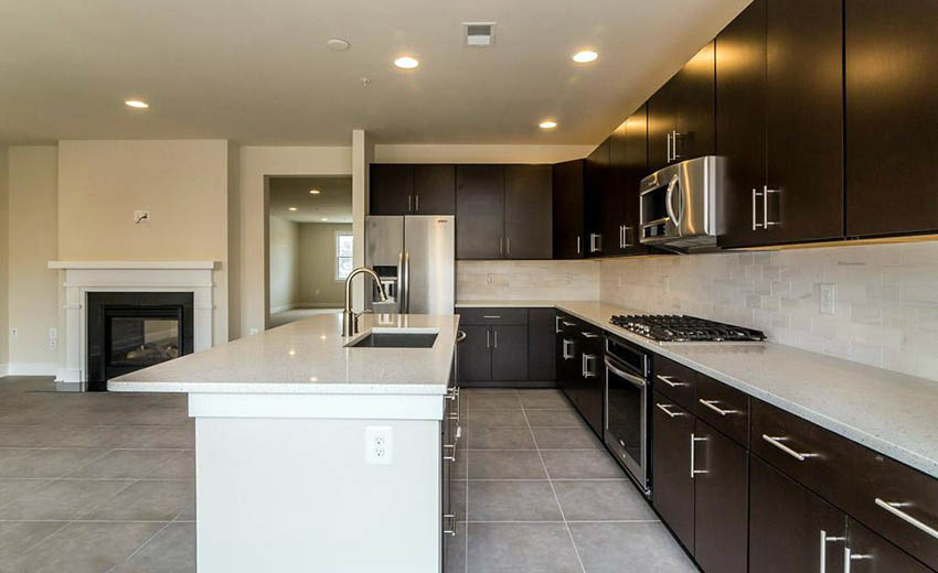 Contemporary kitchen with ceramic tile floors and dark brown cabinets with white island