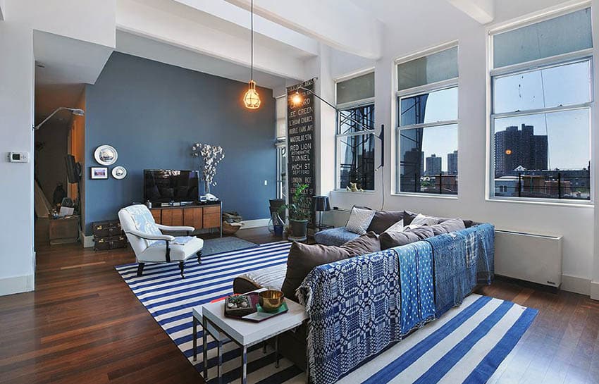 Contemporary living room with navy blue accent wall, wood flooring, high ceilings and large window views