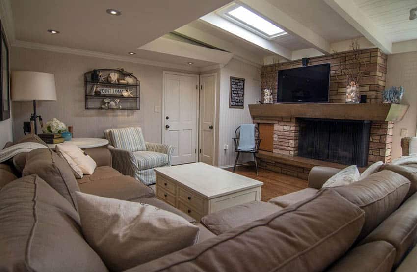 Cottage living room with shiplap walls stone fireplace wood floors and large light brown sectional couch