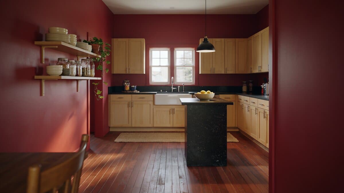 Deep red walls framing light maple cabinets and a black speckled granite island