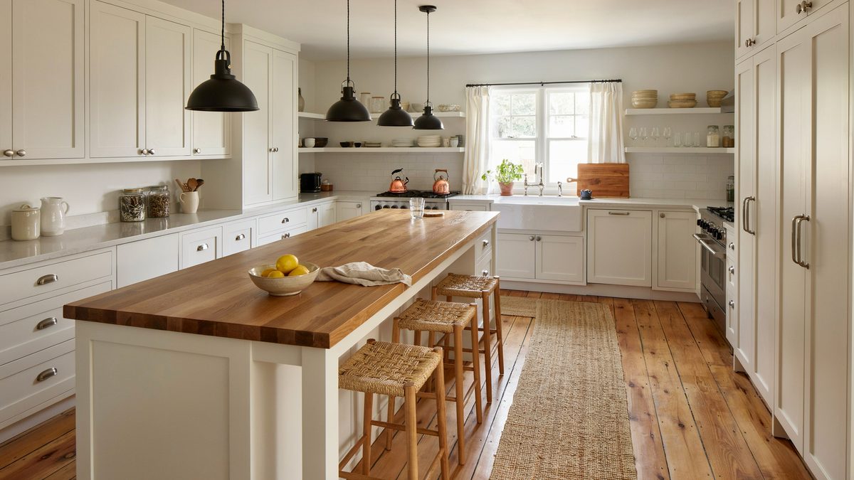 Ivory cabinets and a long walnut breakfast bar on wide oak planks