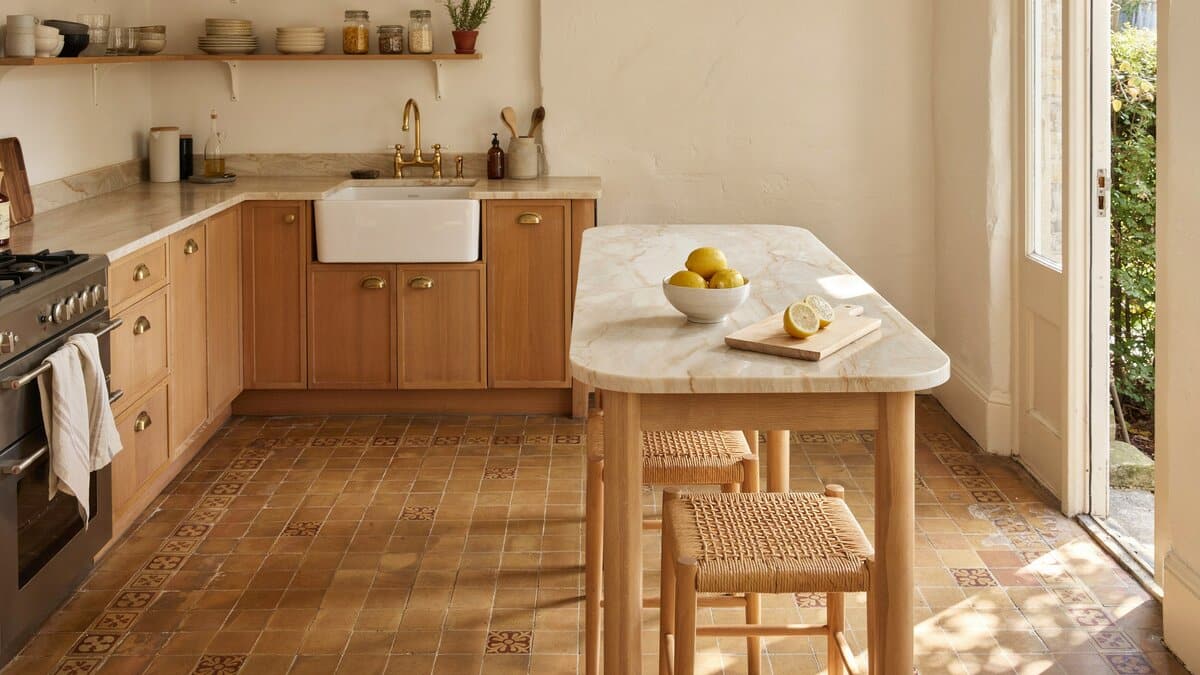 Patterned terracotta floor tiles running under oak cabinets and a pale marble counter