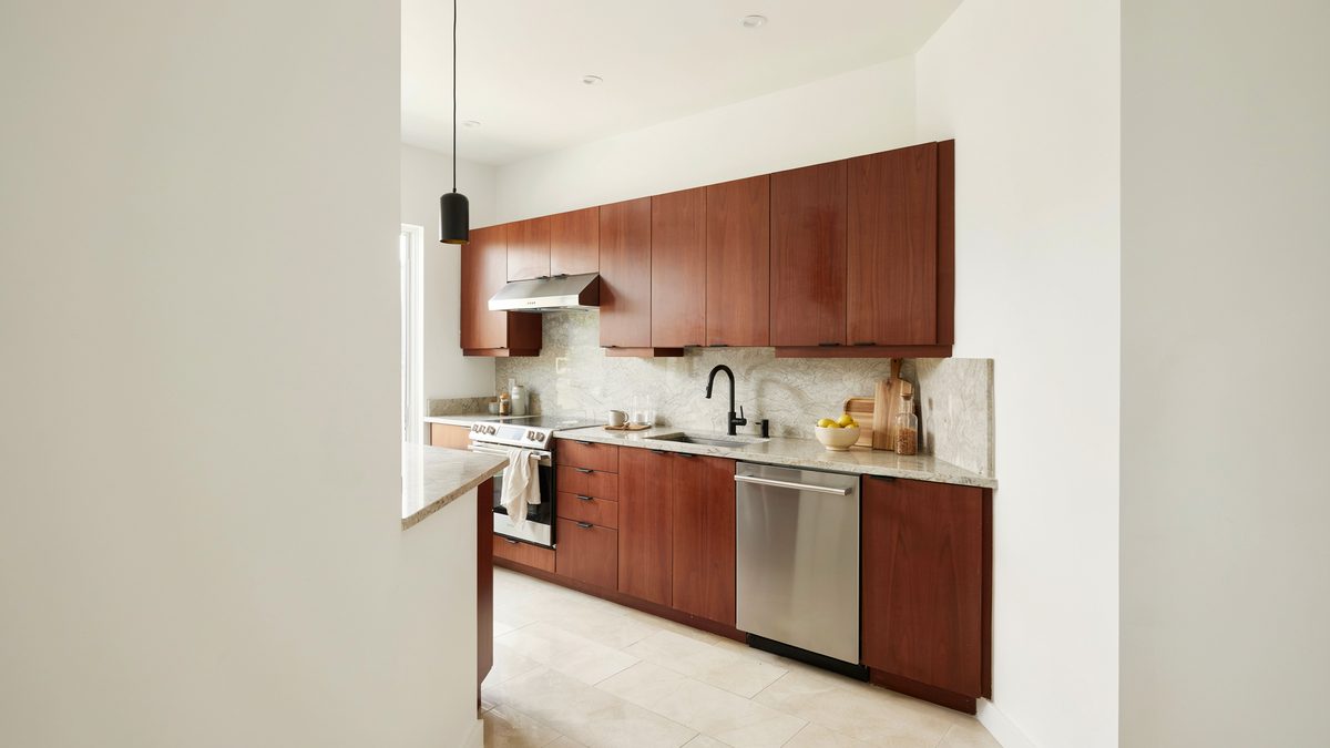 Glossy cherry galley kitchen with white marble backsplash and stainless dishwasher