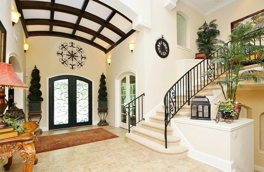 Home entryway with console table, marble floors and staircase with black railing