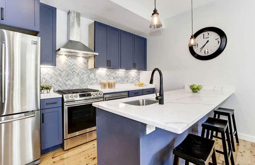 Kitchen with painted blue cabinets and white backsplash and quartz countertop peninsula