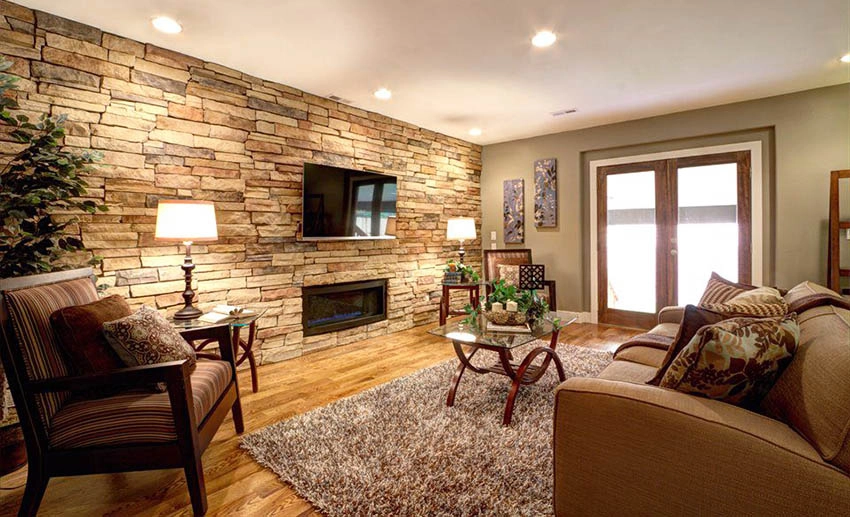 Room with stone tile wall, brown area rug and wood floors
