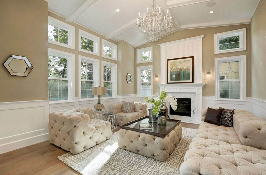 Luxury living room with tan paint white wainscoting wood flooring fireplace and chandelier