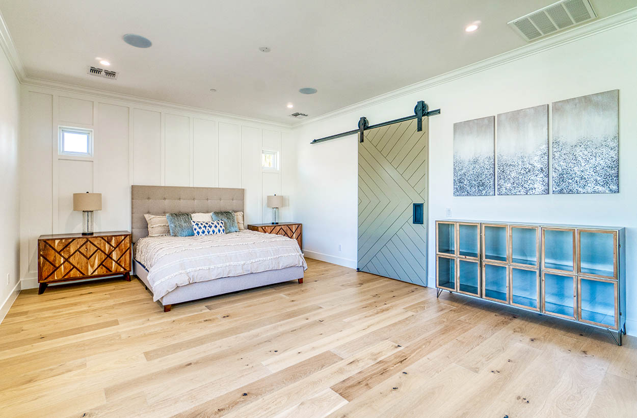 Master bedroom with light hardwood flooring green sliding barn door