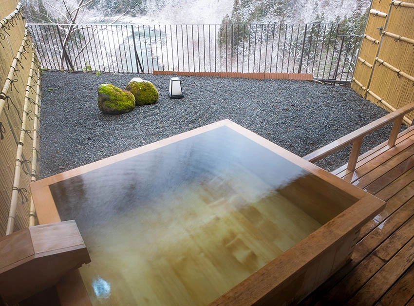 Outdoor Japanese soaking tub with rock garden views