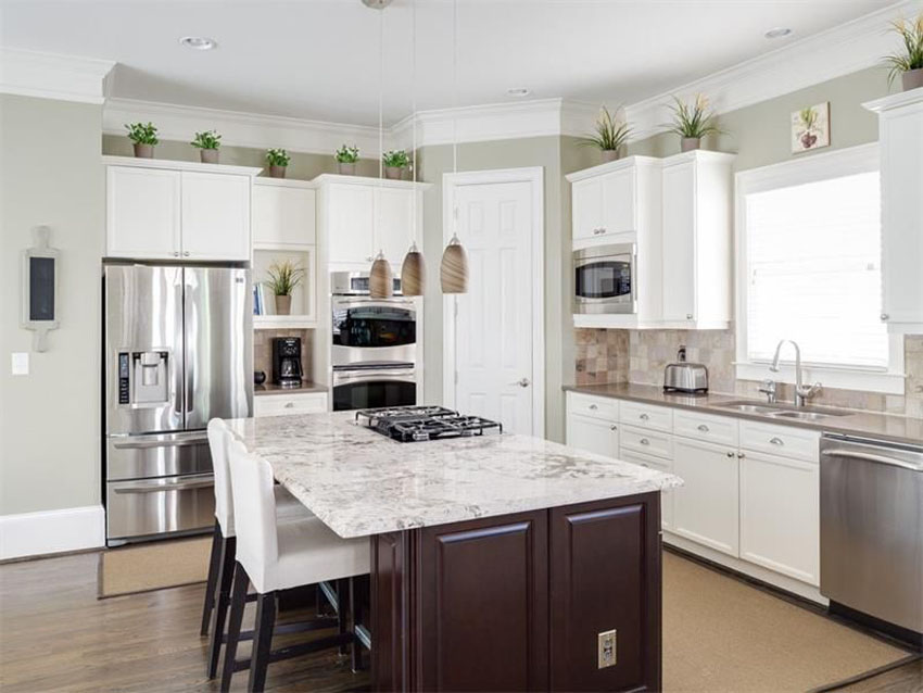 Traditional Kitchen With Plants Above White Cabinets And Brown Island 