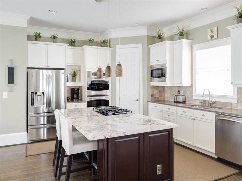 Traditional kitchen with plants above white cabinets and brown stained wood island