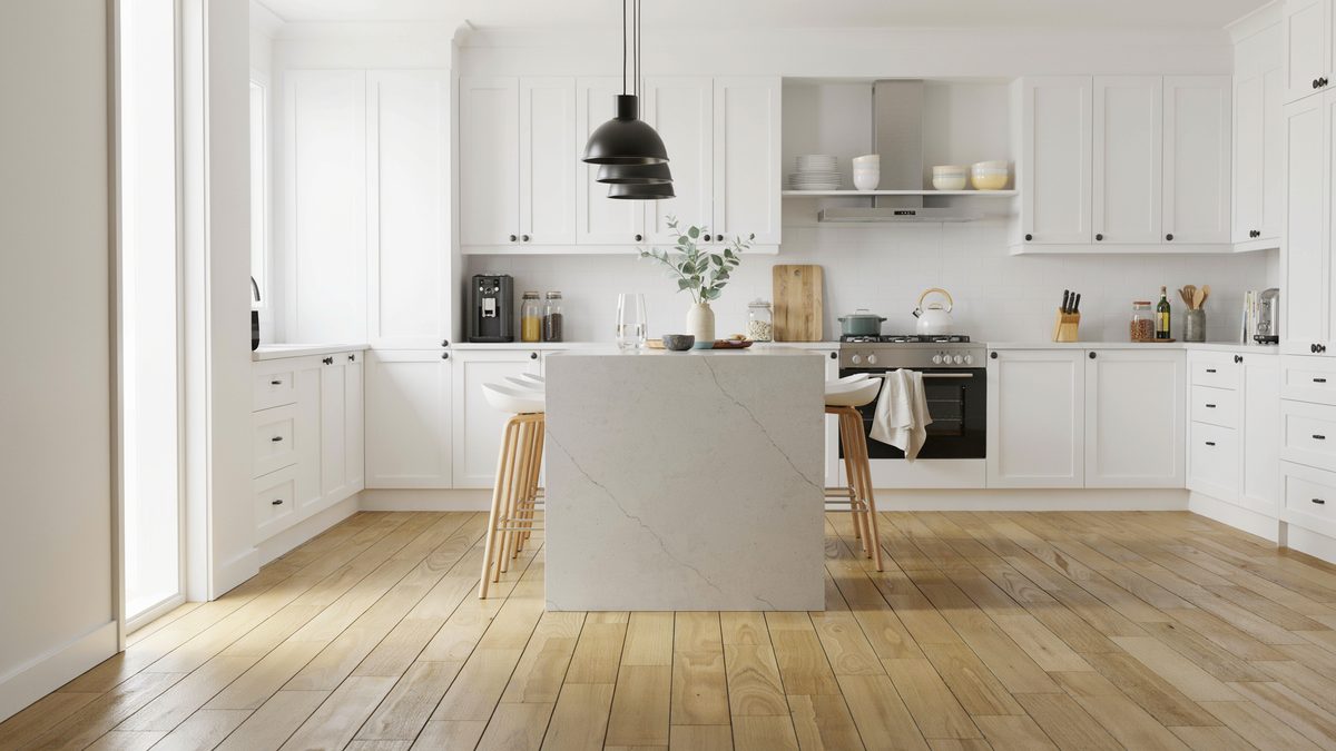 Light bamboo floors in a white kitchen with quartz island and black pendant