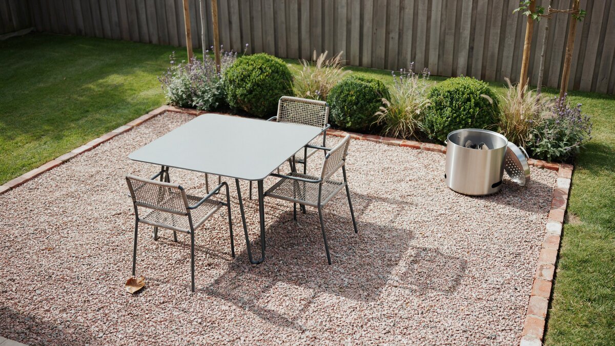 Metal dining set on pea gravel framed by a red brick border