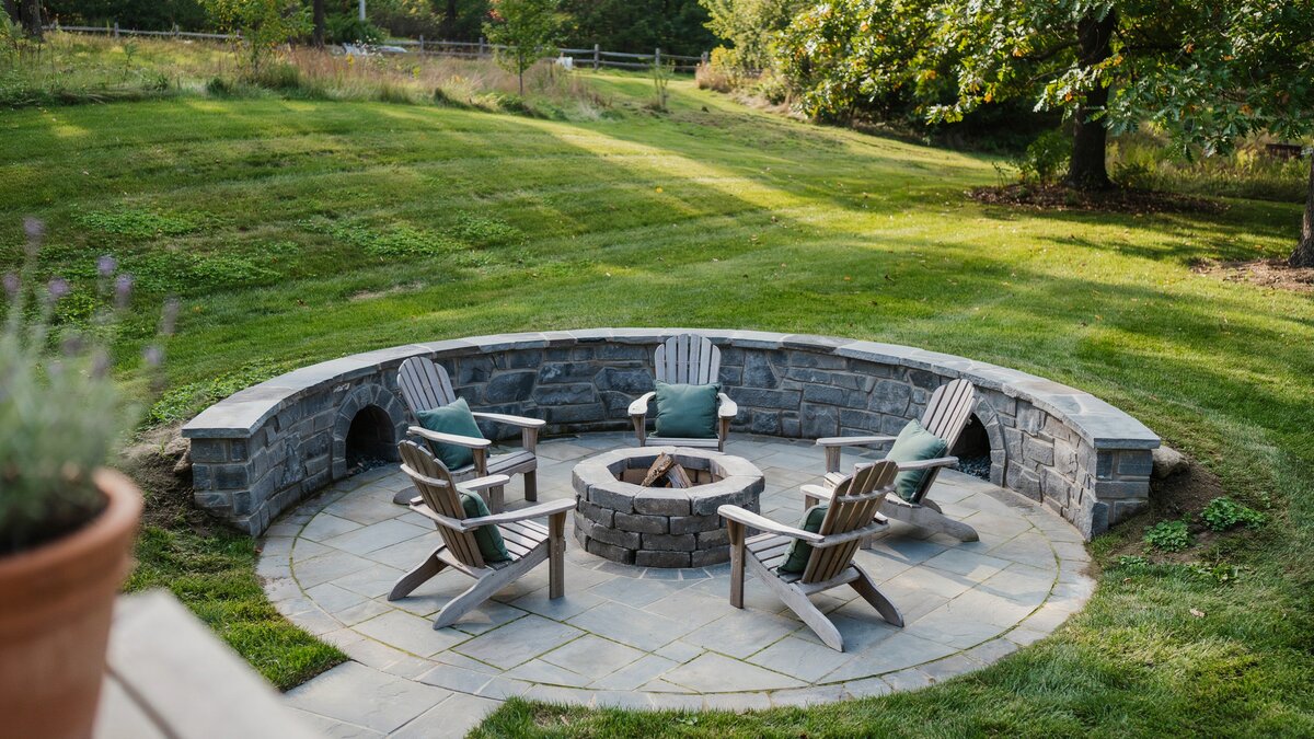 Sunken bluestone circle with stacked stone wall and four Adirondack chairs