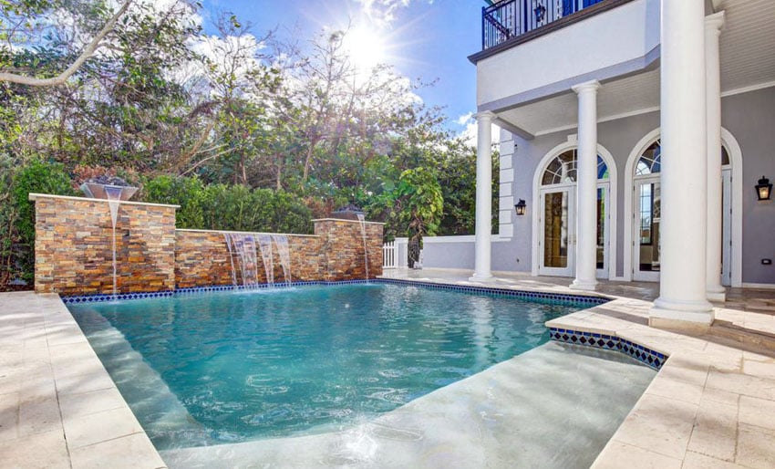 Classic swimming pool with stacked stone wall with waterfalls