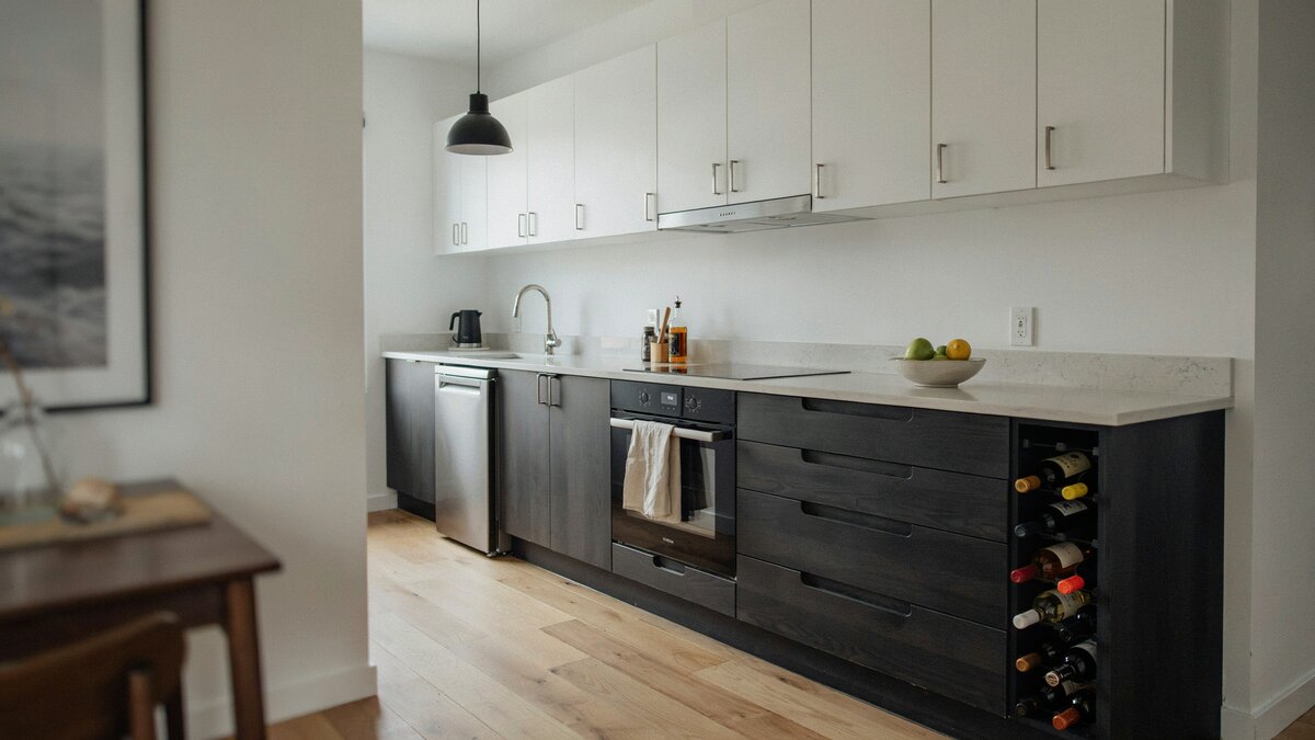 Compact galley pairs white upper cabinets with a black base run and wine storage