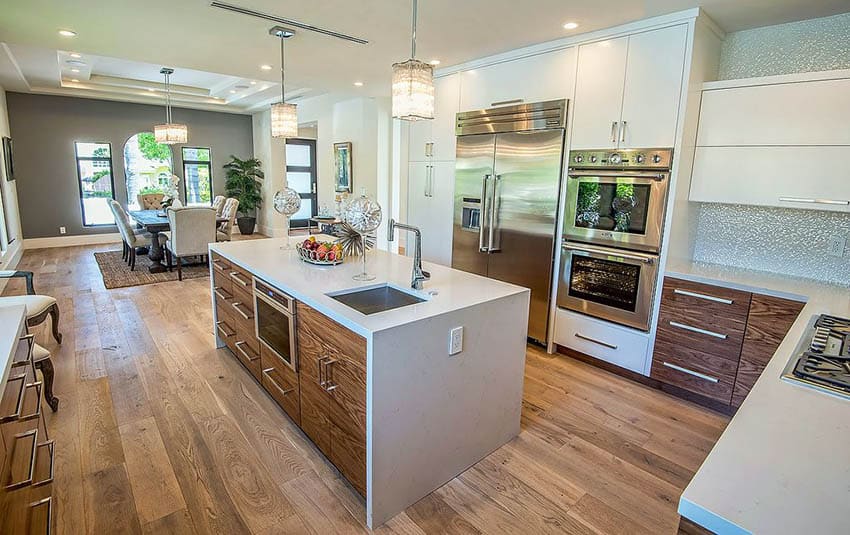 Kitchen with two tone brown and white cabinets and synthetic quartz waterfall island